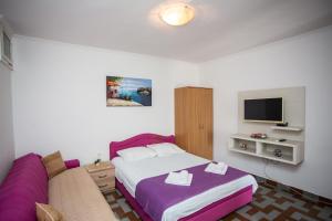 a bedroom with a bed and a couch and a tv at Apartments Jelena Ulcinj in Ulcinj