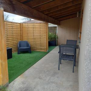 patio z 2 krzesłami, stołem i trawą w obiekcie Chambre d'hôte indépendante près de la jalle w mieście Martignas-sur-Jalle