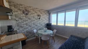 een keuken met een tafel en stoelen in een kamer met uitzicht op de oceaan bij residence du bord de mer 9 appartements face a la mer in Le Tréport
