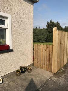 a wooden fence next to a house with potted plants at Rosie's Pad in Mayo