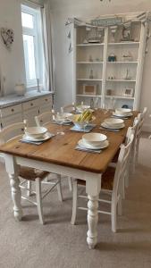 un tavolo di legno con piatti e bicchieri sopra di Ivy Cottage Seahouses Seaside Hot Tub Retreat a Seahouses