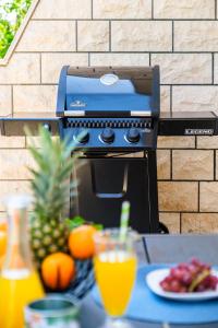 a grill with a plate of fruit and drinks on a table at Villa Josipa with Private Heated Pool & Close to Beach in Supetar
