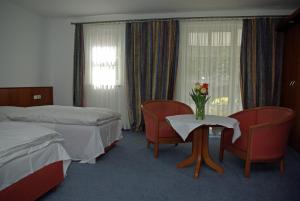 a hotel room with two beds and a table with flowers on it at Hotel Alte Brücke in Bad Homburg vor der Höhe