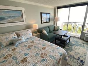 a bedroom with a bed and a couch and a table at Beachfront Islander East Studio in Galveston