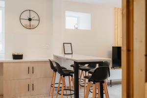 cocina con mesa, sillas y reloj en Charmant T3 en Centre Ville #1 en Embrun
