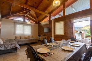 a dining room with a table and a living room at Cabañas Noscohue in Villa General Belgrano