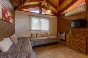 1 dormitorio con 1 cama, ventana y TV en Cabañas Noscohue en Villa General Belgrano