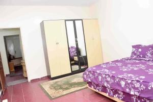 a bedroom with a purple bed and a mirror at Jolie Maison in Nouakchott