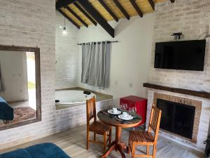 a living room with a table and a fireplace at Chalé Vila do Aeroporto in Monte Verde