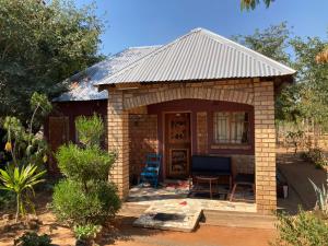 een klein bakstenen huis met een veranda en een patio bij Nakawa Community Campsite in Kazungula