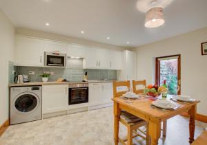 a kitchen with a table and a washing machine at Oak Lodge Cottage in Grasmere