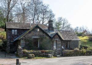 an old stone house sitting on the side of a road at Oak Lodge Cottage in Grasmere