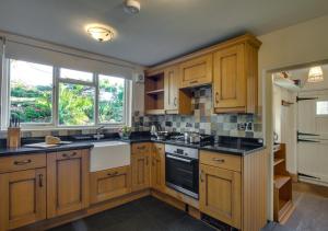 a kitchen with wooden cabinets and black counter tops at Slaters Cottage in Little Langdale
