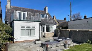 a white house with a patio in front of it at Ivy Cottage Seahouses Seaside Hot Tub Retreat in Seahouses