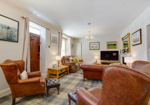 a living room with leather furniture and a tv at Brookside Cottage in Windermere