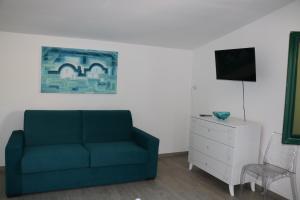 a living room with a blue couch and a white dresser at Albergo"Villa Biscotti" in Peschici