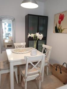 a white dining room table and chairs with flowers on it at Apartamentos Playa de Moncofa in Moncófar