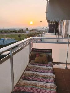 a balcony with a bench with a sunset in the background at Apartamentos Playa de Moncofa in Moncófar