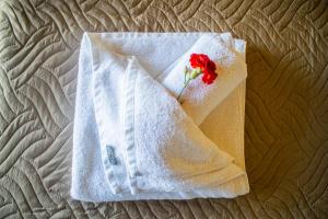 a white robe with a red rose on top of a bed at Traditional Mount Retreat - Ano Pavliana - Corfu in Áno Pavliána