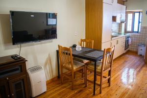 a kitchen with a dining room table with chairs and a television at Traditional Mount Retreat - Ano Pavliana - Corfu in Áno Pavliána