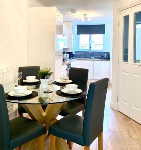 a dining room with a table and chairs and a kitchen at 3 bedroom - 2 bathroom Townhouse in Corstorphine Near Murrayfield Stadium - Direct Bus To Edinburgh City Centre in 20 Minutes - Two Private Parking Spaces - Private Sunny Garden - Recently Refurbished in Edinburgh