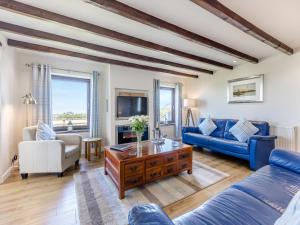 a living room with a blue couch and a table at Bay View Cottage in Llanon