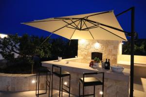 - une table avec des chaises et un parasol sur la terrasse dans l'établissement Malia Holiday Villa, à Conversano