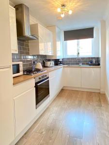 a kitchen with white cabinets and a wooden floor at 3 bedroom - 2 bathroom Townhouse in Corstorphine Near Murrayfield Stadium - Direct Bus To Edinburgh City Centre in 20 Minutes - Two Private Parking Spaces - Private Sunny Garden - Recently Refurbished in Edinburgh