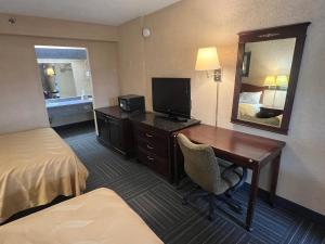a hotel room with a desk and a bed and a mirror at The Lodge Hotel and Banquets in Bridgeton