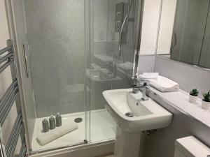 a white bathroom with a sink and a shower at 3 bedroom - 2 bathroom Townhouse in Corstorphine Near Murrayfield Stadium - Direct Bus To Edinburgh City Centre in 20 Minutes - Two Private Parking Spaces - Private Sunny Garden - Recently Refurbished in Edinburgh