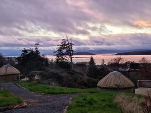 Kelburn Yurts في Fairlie: مجموعة من الخيام في حقل مع بحيرة