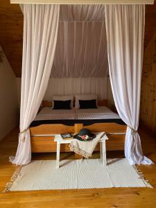 a bedroom with a bed with a curtain and a table at Kuca Ribarev san in Beočin