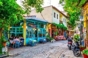 una calle adoquinada en un casco antiguo con mesas y sillas en Sweet Home Ano Poli en Tesalónica