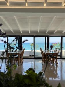 ein Esszimmer mit Tischen, Stühlen und Meerblick in der Unterkunft Kymata Hotel in Platamonas