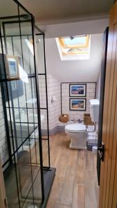 a bathroom with a toilet and a glass door at High Street Apartment in Windermere
