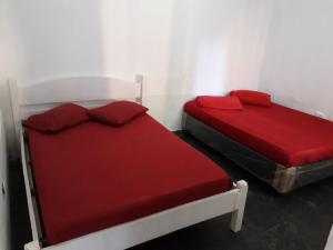 2 Betten mit roter Bettwäsche in einem Zimmer in der Unterkunft Hostel Canto de Bertioga in Bertioga