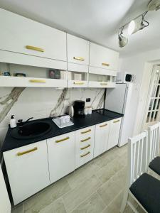 a kitchen with white cabinets and a black counter top at Luxor Apartament Sibiu in Sibiu