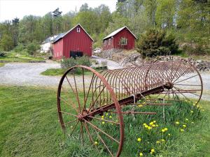 un viejo tractor en un campo con dos graneros rojos en Villa Ulvatorp nära Varberg och Ullared, en Veddige