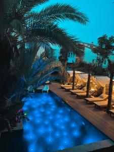 a swimming pool with palm trees and lounge chairs at The ABC Hotel in Alaçatı