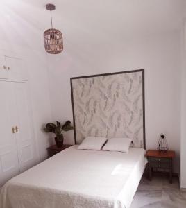 a bedroom with a white bed with a large headboard at Florencio Quintero Home in Seville