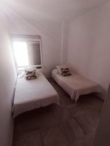 two beds in a white room with a window at Florencio Quintero Home in Seville