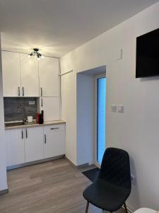 a white kitchen with a black chair and a window at Easy Living Apartments - Old Town in Braşov