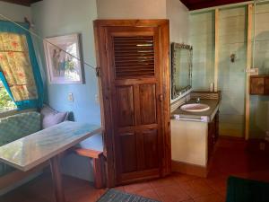 a bathroom with a sink and a wooden door at Treehouse Apartment at La Lodge at Long Bay in Corn Islands