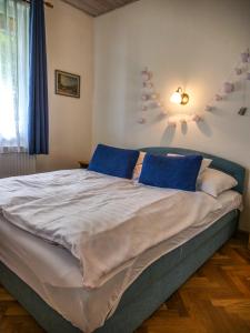 1 dormitorio con 1 cama grande con almohadas azules en Villa Gabriella - Vízparti, en Balatonboglár