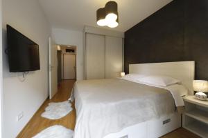 a bedroom with a large bed and a flat screen tv at A blok - One bedroom apartment in Belgrade