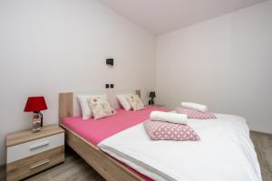 een slaapkamer met een groot bed met roze en witte lakens bij Apartment Ena in Crikvenica