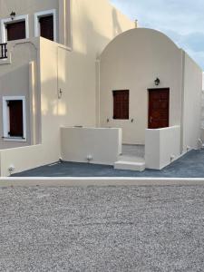 een wit gebouw met twee deuren aan de zijkant bij Tarelis Apartments & Studios in Kamari