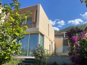 a house with a glass facade with mountains in the background at Green Coast 136 in Dhërmi