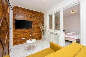 een woonkamer met een tv aan een bakstenen muur bij Apartment Ena in Crikvenica