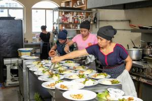 un grupo de personas preparando platos de comida en una cocina en Los Elementos en Santa Cruz La Laguna